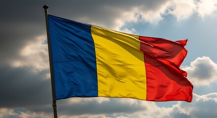 Romanian flag waving proudly against a dramatic cloudy sky, symbolizing national pride and identity on a bright, windy day.