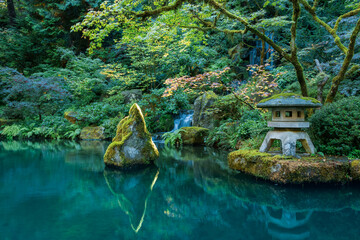 Scenic pond and rock lantern in Portland Japanese garden in early autumn time.