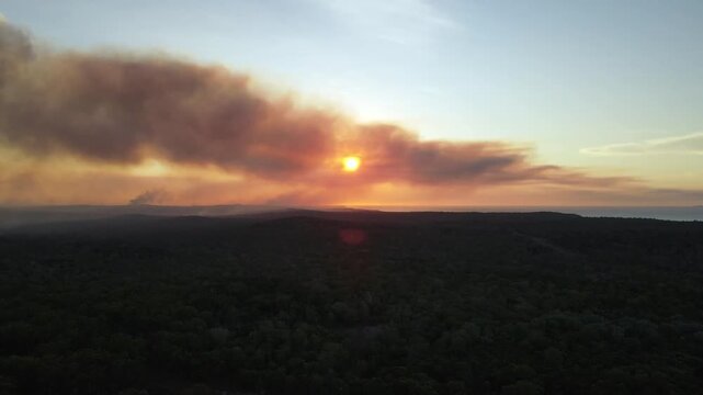 Aerial sunset clip over Australian bushland with sun setting behind smoke from bushfires.