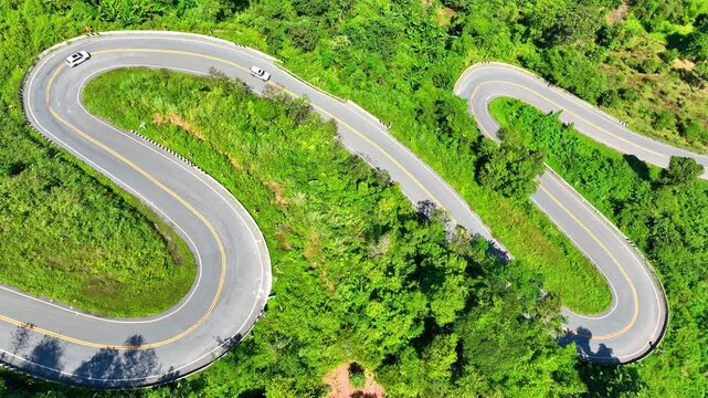 Drone aerial shot of a serpentine road across steep mountains, reflecting accident hazards, driving risks, adventure, perseverance, awareness, safety, and nature&rsquo;s unpredictability. Thailand. 4K.
