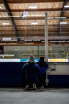 Child Boy and Dad Admiring Skaters Together on Indoor Ice Rink