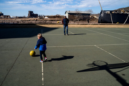 Toddler Boy and Father Playing with Basketball on Outdoor Court
