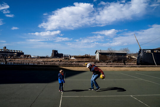 Father Dribbling Basketball with Son on Outdoor Sport Court in Sun