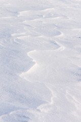 Windblown snow displaying curved textures of light and shadow