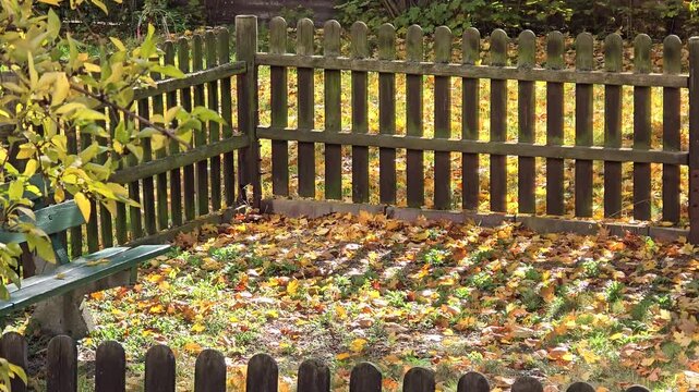 Sunny autumn playground with wooden bench and falling yellow leaves