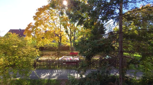 Sunny autumn playground with sandbox and falling yellow leaves