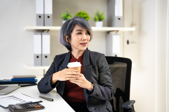 Business woman in suit taking a coffee break in  office.