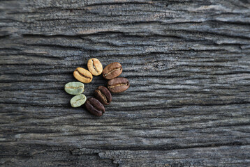 Color roast level of green coffee bean to dark roasted bean on wooden board. top view.