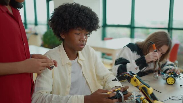 Group of high school students building and programming electric toys and robots project at classroom. Innovative technology development