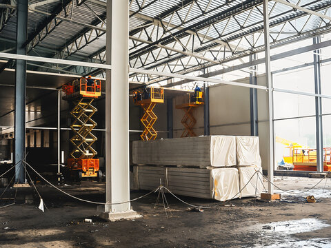 Construction site interior with scissor lifts and building materials