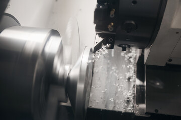 CNC lathe machine or turning machine cutting parts at the steel shaft. Elements cutting process on the Computer Numerical Control lathe machine. 