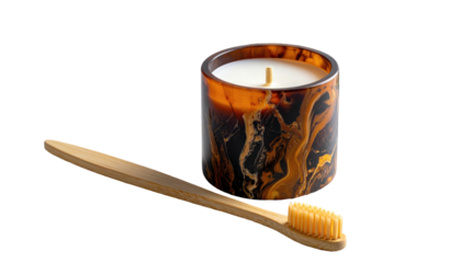 Candle sits next to a toothbrush, on a black backdrop. Marble-like candle holder adds to the eco-friendly aesthetic