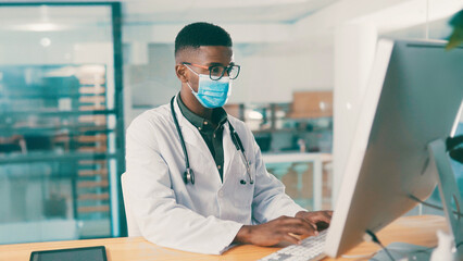 Black man, doctor and typing on computer in clinic for medical history, report or PPE for safety....