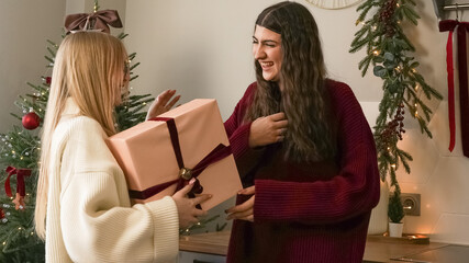 Friends exchange gifts in a cozy home decorated for Christmas celebration