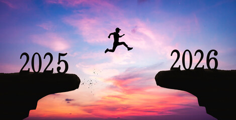 Silhouette of a man jumping over the gap between 2025 and 2026. New year concept.