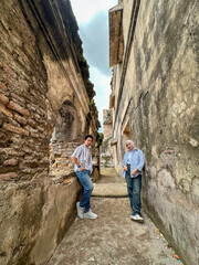Two tourists stand near the ancient stone walls of Taman Sari Water Castle, enjoying the scenery
