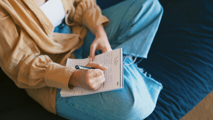 Creative, writing and hands with journal, sofa and planning for novel in lounge, inspiration or idea. Home, writer and person with notebook for brainstorming, relax and artist with project on couch