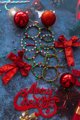 Christmas themed handmade bracelets on a stone background surrounded by Christmas balls and other decorations.
