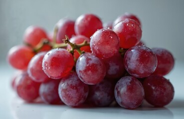 Fresh bunch of ripe red grapes covered in water droplets on clean white surface. Close up on juicy sweet fruit. Organic berries for healthy raw vegan diet snack winemaking. Autumn harvest seasonal