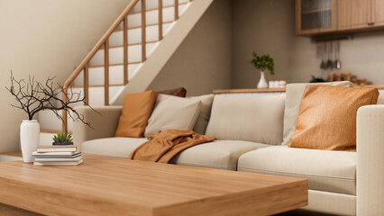 Books and vase on wooden table and sofa couch aside staircase in living room of modern house apartment.