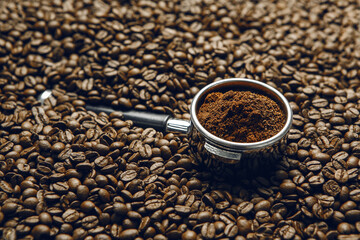 Freshly Ground Coffee in Portafilter on Roasted Coffee Beans Close Up
