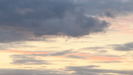 The sky at dawn or sunset with clouds in pink and purple tones is a natural scene where the soft light of the sun penetrates dark and light clouds.