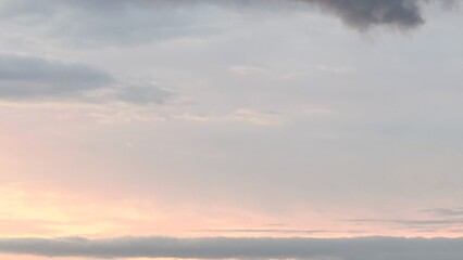 The sky at dawn or sunset with pastel clouds and contrasting light is a natural scene with soft pink, orange, and blue hues combined with dark clouds, creating a deep atmosphere of calm, tension,