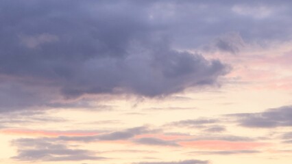 The sky at dawn or sunset with clouds in pink and purple tones is a natural scene where the soft light of the sun penetrates dark and light clouds.