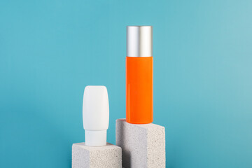Skin care or sunscreen cosmetic with stylish props on blue background.