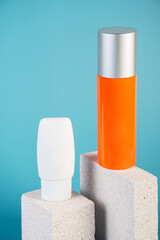 Skin care or sunscreen cosmetic with stylish props on blue background.