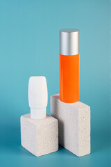 Skin care or sunscreen cosmetic with stylish props on blue background.