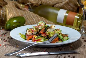 salad with zucchini and tomatoes with cheese on a plate on a background of a bottle of white wine