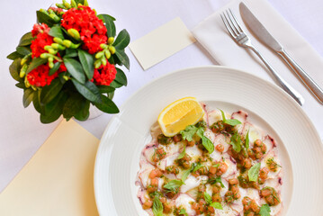 squid carpaccio in a plate with capers on a table with food decor