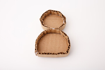 Two glued cardboard shapes forming figure of a snowman or reindeer base made corrugated paper on white background. DIY craft step-by-step process. Studio macro photography. Design for craft tutorial,