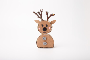 Handmade reindeer figure made of cardboard circles with branch antlers, paper ears, button details, and drawn face on white background. Studio craft photography. Christmas and winter holiday concept