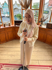 A woman is singing into a vintage microphone in a warm, inviting space filled with antique decor