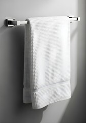 A fluffy white bath towel is neatly folded and hung on a modern chrome towel bar mounted on a textured wall.