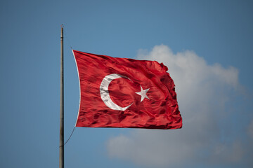 The national flag of Turkey waves in the wind against a blue sky