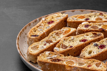 Italian Almond Biscotti biscuits in a rustic home made pottery bowl. Studded with almonds and cranberries, these twice-baked treats are aromatic and inviting. Ideal.