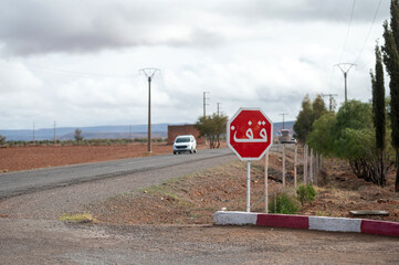 Stop sign in Arabic along a quiet road in rural Morocco on a cloudy day
