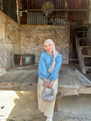 A woman with a headscarf poses in a rustic setting, showcasing traditional style and warm light