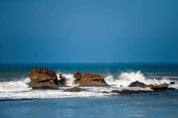 Waves break on rocky outcrops along Essaouira's coastline, creating a dynamic scene.