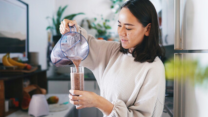 Pouring, smoothie and woman with blender, kitchen and liquid with gut health benefits, diet and home. Beverage, nutrition and person with equipment for protein shake, detox and wellness with drink