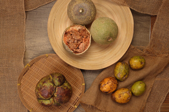 Unique exotic rare Asian fruit green elephant apple chalta ou tenga amra kedondong Ambarella wood apple kod bel on rustic wood jute rope table background