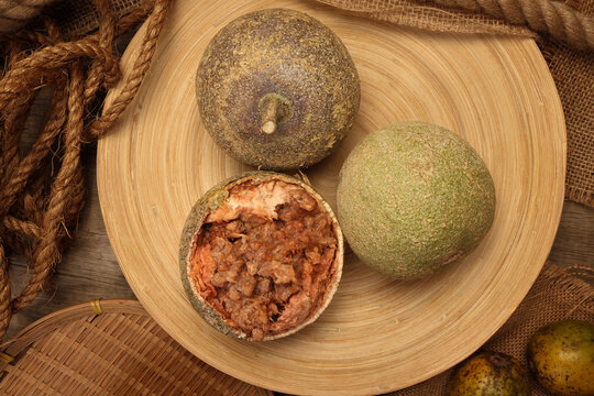 Hard shelled rare exotic fruit sour tangi wood apple kod bel on rustic wooden plate background