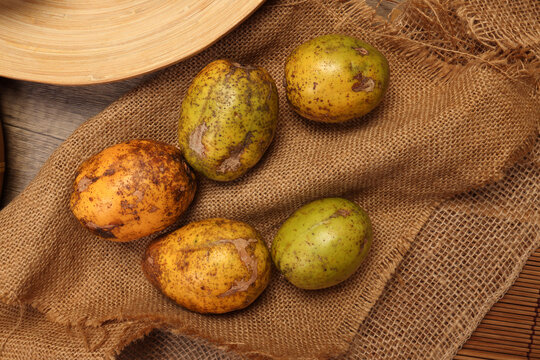 Unique exotic Asian ripe yellow gold green fruit amra kedondong Ambarella on rustic jute fabric  background
