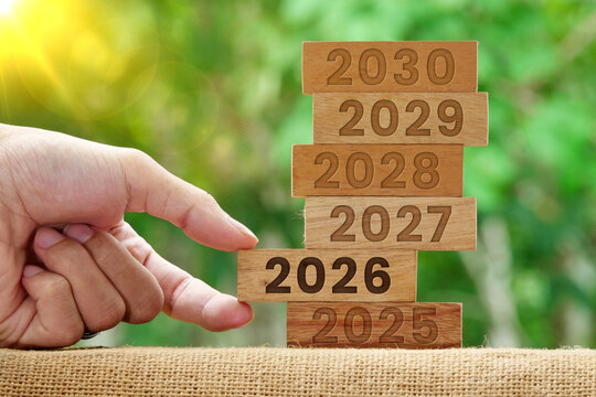 Hand pulling a wooden block that says 2026 on a wooden Tower with the numbers 2025-2030. Business strategy. New year concept - Powered by Adobe
