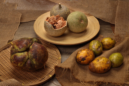 Unique exotic rare Asian fruit green elephant apple chalta ou tenga amra kedondong Ambarella wood apple kod bel on rustic wood jute rope table background
