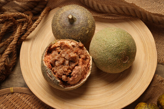 Hard shelled rare exotic fruit sour tangi wood apple kod bel on rustic wooden plate background