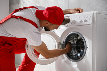 Professional repairman fixing broken washing machine indoors